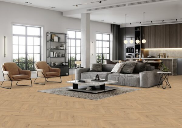 Et rummeligt køkkenalrum med en stor, smuk grå sofa og to komfortable stole i en varm karamel farve. Et elegant marmorbordt. Gulvet er prydet med et smukt sildebensmønster i varm eg farve.